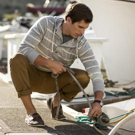 man tying boat line to cleat on dock